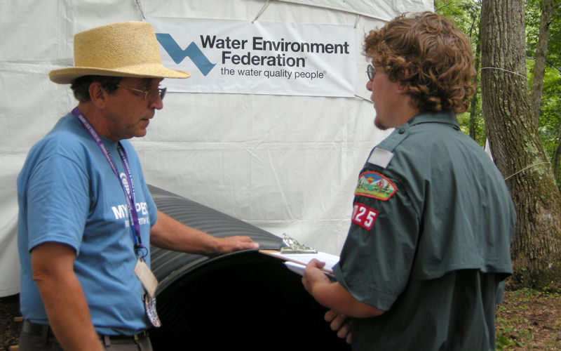 Volunteer John Peplowski from the Beckley (W.V.a) Sanitary Board talks to a Scout in front of the stormwater pipe entrance to WEF’s educational exhibit at the jamboree. WEF photo/Harrison.