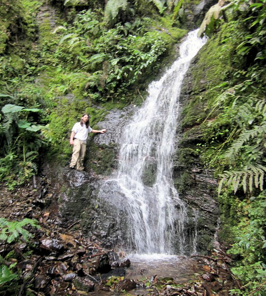 McGuinness stands near the waterfall above the upper campus of Unidad Academica Campesina in Carmen Pampa.  This is the main water supply for the campus. Photo courtesy of Berdanier.