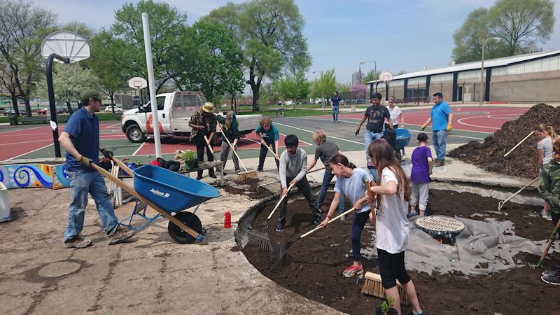 From left, Matthew Sokolowski, CSWEA volunteer, and Barbara McGowan, vice president of the Metropolitan Water Reclamation District of Greater Chicago, work with students and other volunteers to fill the rain garden with soil. Photo courtesy of Natalie Cook.